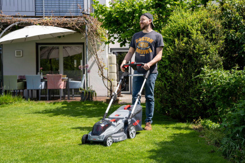 Mann mäht Rasen mit dem IKRA BOSCH Akku Rasenmäher IB-ML 38